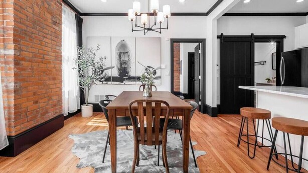 A modern kitchen with a black refrigerator, white countertops, and a hanging light fixture. - OSU & Crew Stadium | Easy Walk | Great Design (Columbus)