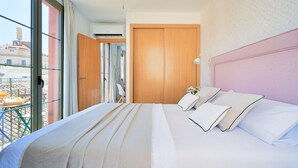 A hotel room with a large bed, a wooden wardrobe, and a view of the city through a large window.