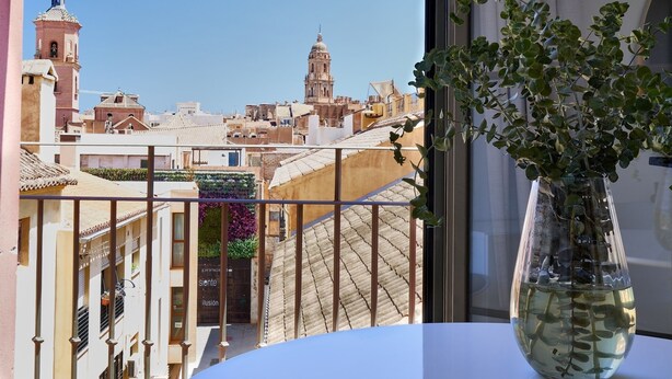 A balcony with a view of a cityscape, including buildings and a church tower.