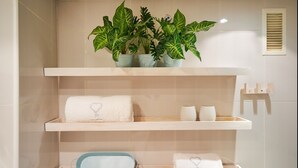 Ein Badezimmer mit drei Holzböden, auf jedem liegen Handtücher und eine weiße Vase.