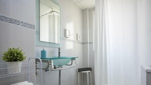 Une salle de bain moderne avec un lavabo en verre, des toilettes blanches et un rideau de douche.