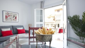 Un salon moderne avec une table en verre, un canapé agrémenté de coussins rouges et un vase décoratif posé sur la table.