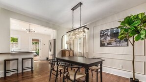 A spacious dining area with a dark wooden table and chairs, a hanging chandelier, and a potted plant. - Private Patio |German Village| Walk Everywhere (Columbus)