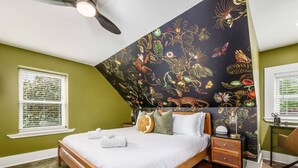 A bedroom with a bed, a nightstand, a desk, and a large wall mural. - Private Patio |German Village| Walk Everywhere (Columbus)