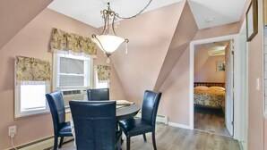 A dining area with a round table, four chairs, a chandelier, and patterned curtains.