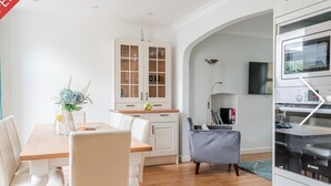 Una cucina moderna con mobili bianchi, un tavolo da pranzo con sedie e un forno a incasso.