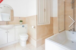 Bathroom features a sink, toilet, and bathtub, with a mirror above the sink and a potted plant on the counter.