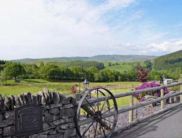 A stone wall with a mailbox, a wooden fence, and a large wheel structure. - Golygfar Mynydd Retreat - Sleeps 6 (Tregaron)