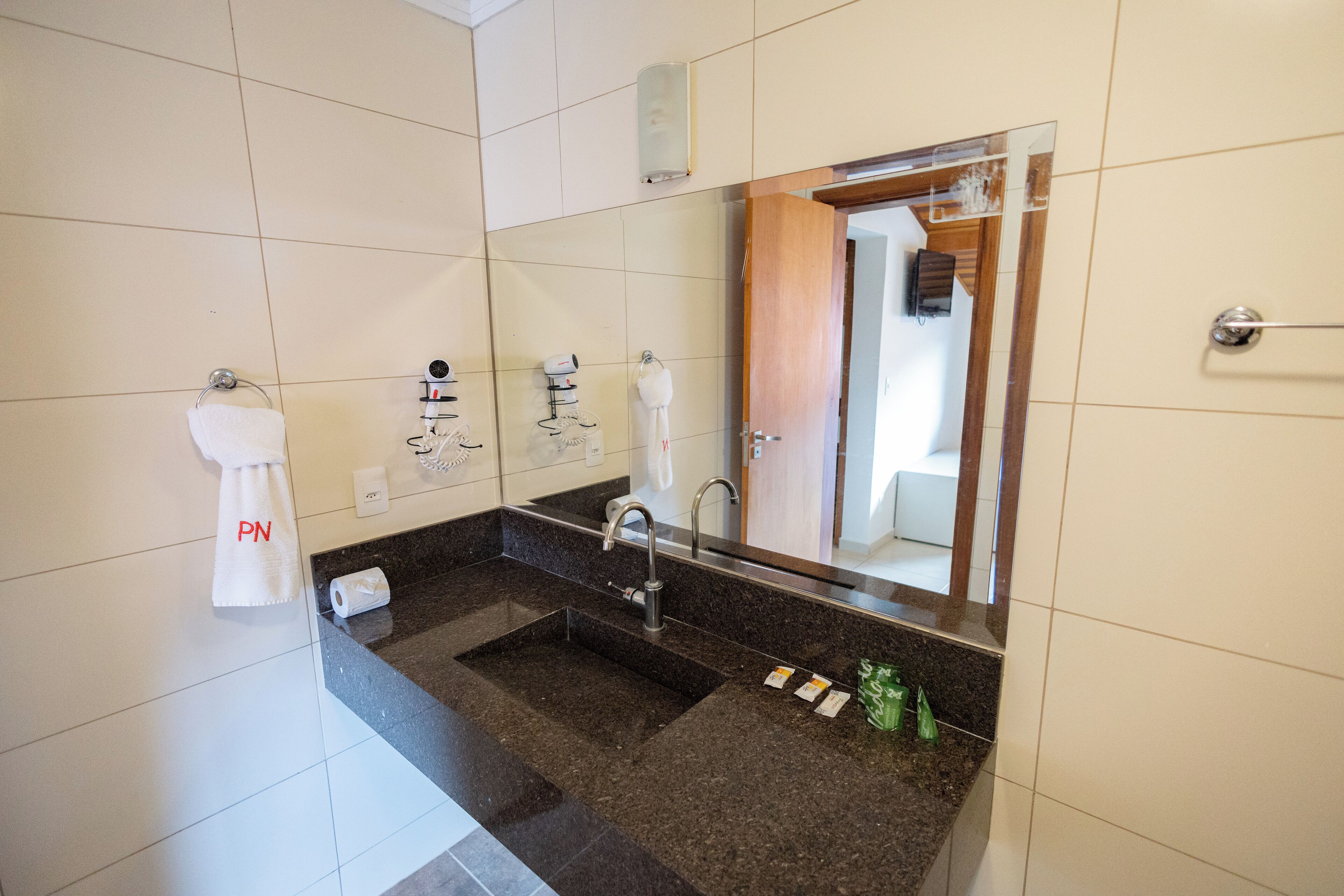 Un baño moderno con un espejo grande, un lavabo y un perchero para toallas.