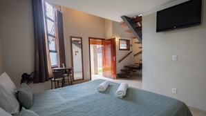 A hotel room with a bed, a desk, and a staircase leading to an upper level. - Pousada Nefelibatas (Águas de Lindóia)