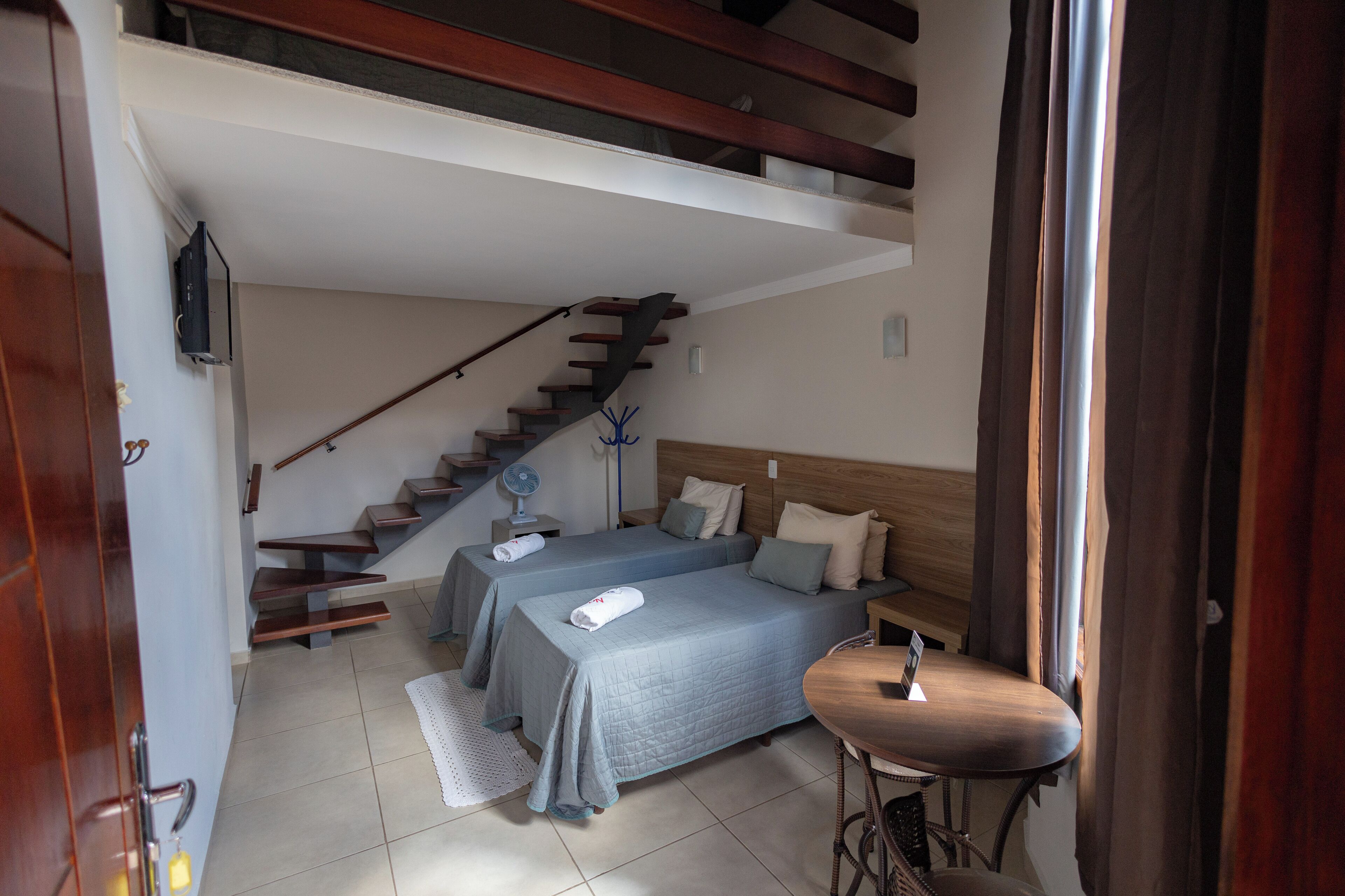 Ein Schlafzimmer mit zwei Betten, einer Holztreppe, einem kleinen Tisch und einem Stuhl.