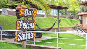 A wooden sign with 'Bar', 'Piscina', and 'Sauna' written on it. - Pousada Nefelibatas (Águas de Lindóia)