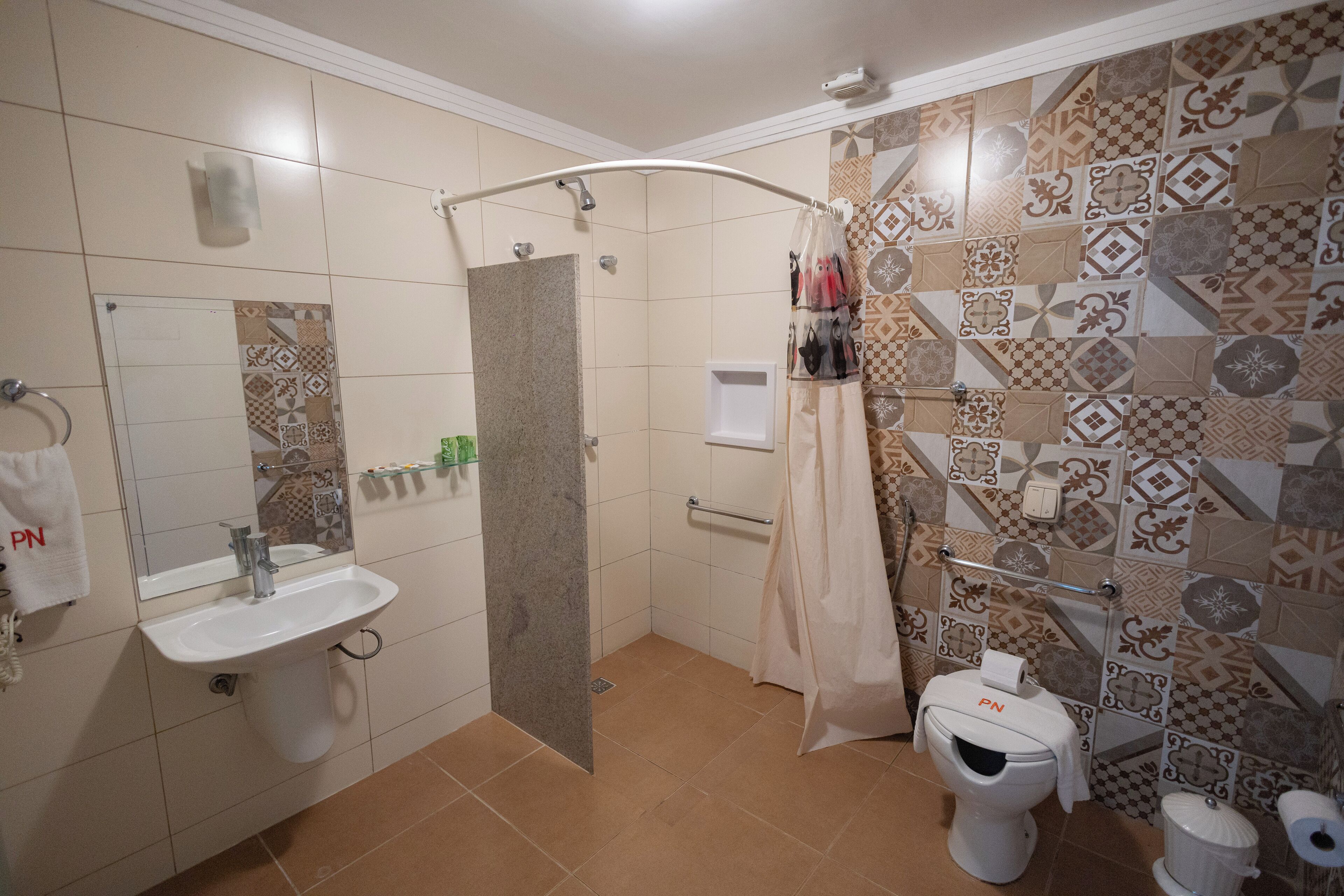 Casa de banho com chuveiro, lavatório, sanita e suporte para toalhas.