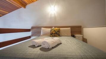 A neatly made bed with a quilted bedspread and two rolled towels.