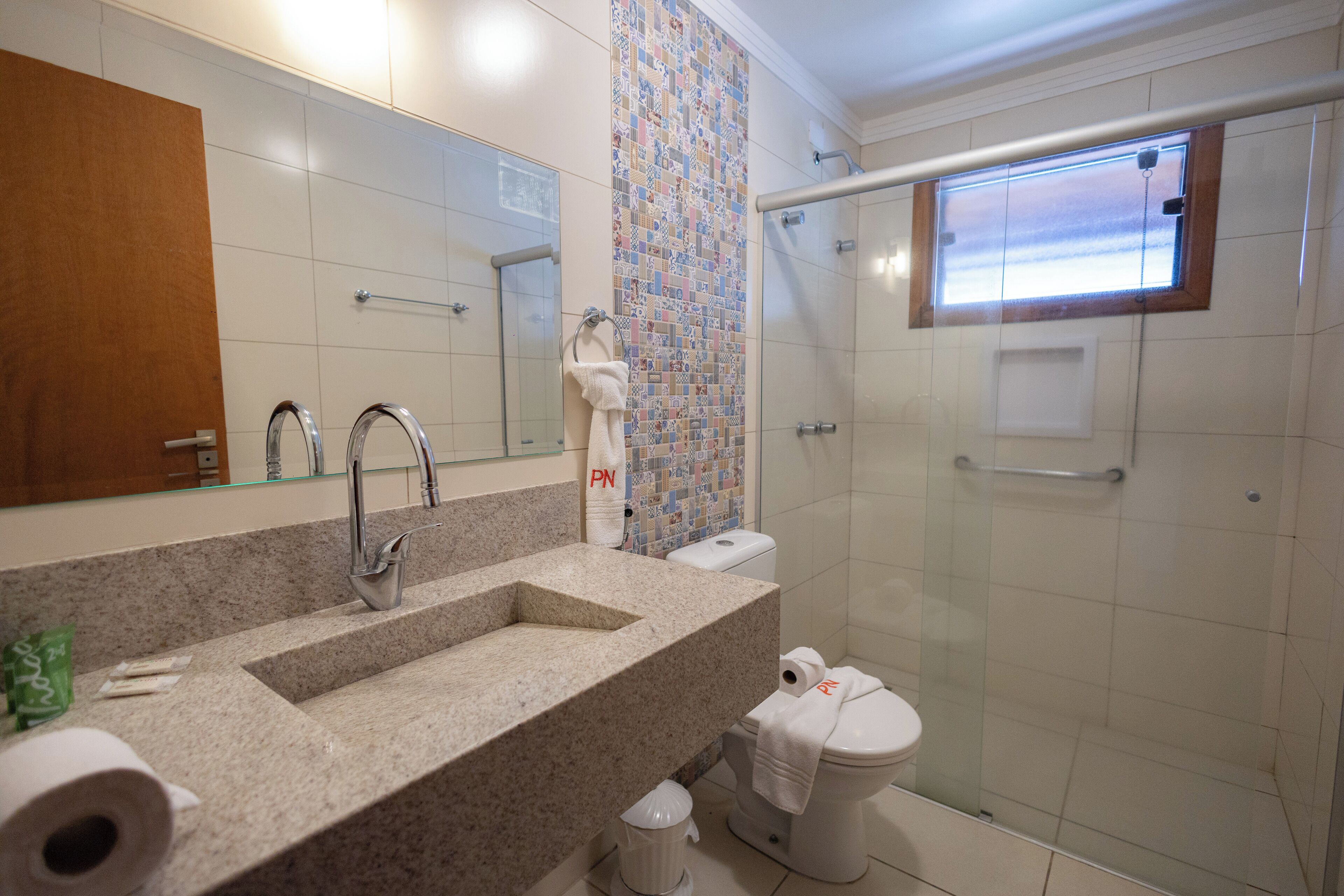 Un baño con lavamanos de granito, inodoro y cabina de ducha.