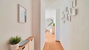 A hallway with a wooden cabinet, a potted plant, and framed pictures on the walls.