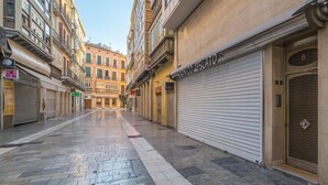 A quiet urban street with closed shops and a clear sky.