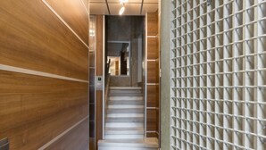 A modern interior with a wooden wall, a textured wall, and a staircase leading to a higher floor.