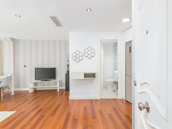 A modern living room with a flat-screen TV, a white cabinet, and a hexagonal wall decoration. - Pic VIII Granada 8 II (Málaga)