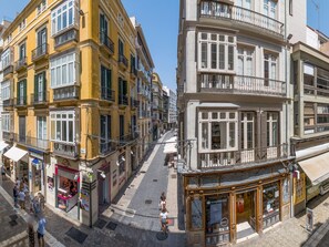 A street view with buildings, shops, and pedestrians. - Pic VIII Granada 8 II (Málaga)