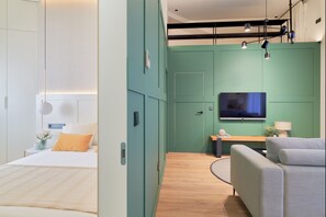 Ein modernes Hotelzimmer mit Bett, Schreibtisch, Fernseher und einer Couch.