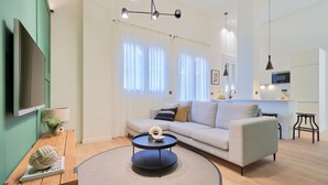 A modern living room with a sofa, round coffee table, and a flat-screen TV mounted on the wall. - iloftmalaga Playamar I (Torremolinos)