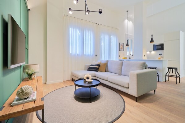 Ein modernes Wohnzimmer mit einer Couch, einem runden Couchtisch und einem flachbildfernseher an der Wand.