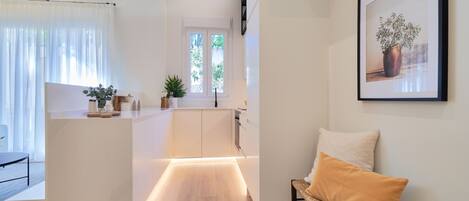A modern kitchen with a central island, a dining area with a bench, and a framed artwork on the wall.