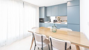 Een moderne keuken met blauwe kastjes, een houten eettafel en een glazen vaas.