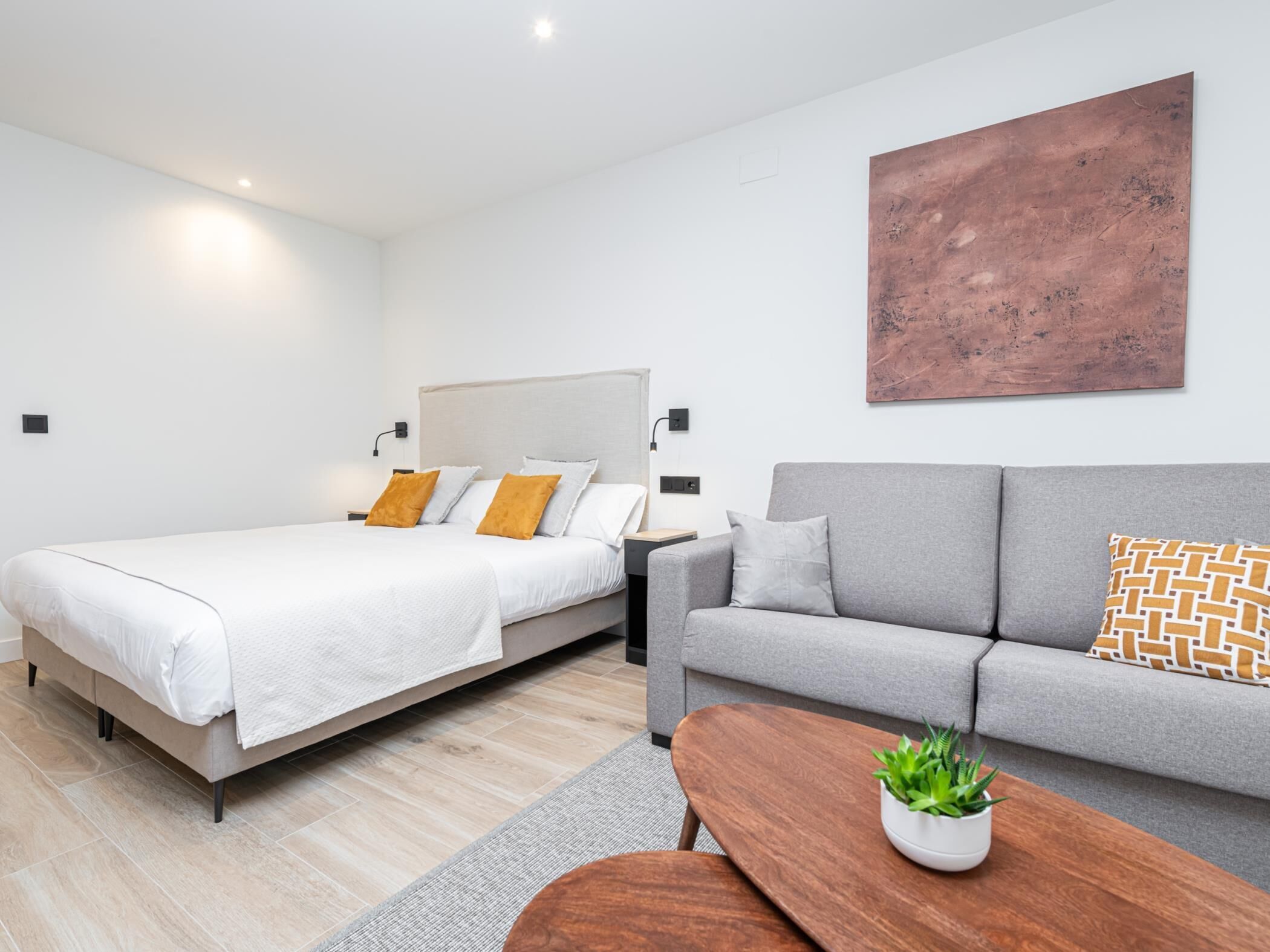 A modern bedroom with a bed, a grey sofa, and a coffee table.