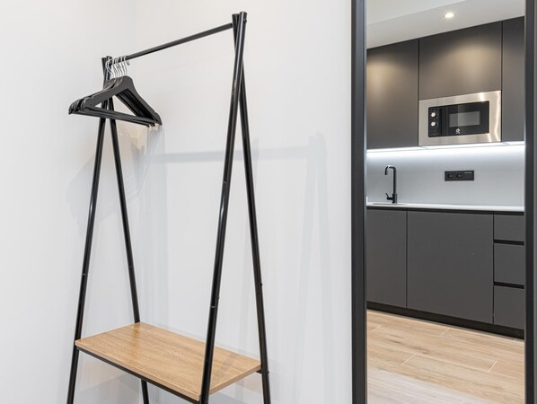 A modern kitchen with a built-in microwave and a wooden shelf unit with a hanging rack.
