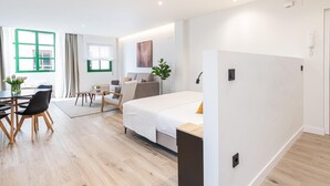 A modern hotel room with a bed, a desk, and a dining area. - Barroso II - iloftmalaga (Málaga)
