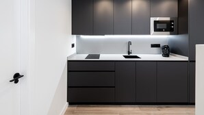 A modern kitchen with dark cabinetry, a built-in microwave, and a sleek countertop. - Barroso II - iloftmalaga (Málaga)