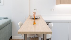 Eine moderne Küche mit einem Holztisch, weißen Stühlen und einer Vase mit Schilfhalmen.