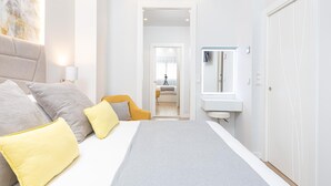 Ein modernes Hotelzimmer mit einem großen Bett, einem Nachttisch, einem Spiegel und einem Kleiderschrank.