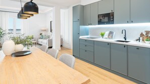 A modern kitchen with grey cabinets, a wooden dining table, and pendant lighting.