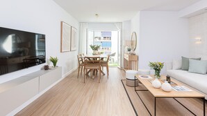 Una sala moderna con televisor de pantalla plana, mesa de comedor de madera y un sofá.