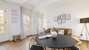 A modern dining area with a round table, wooden chairs, and a vase with flowers.