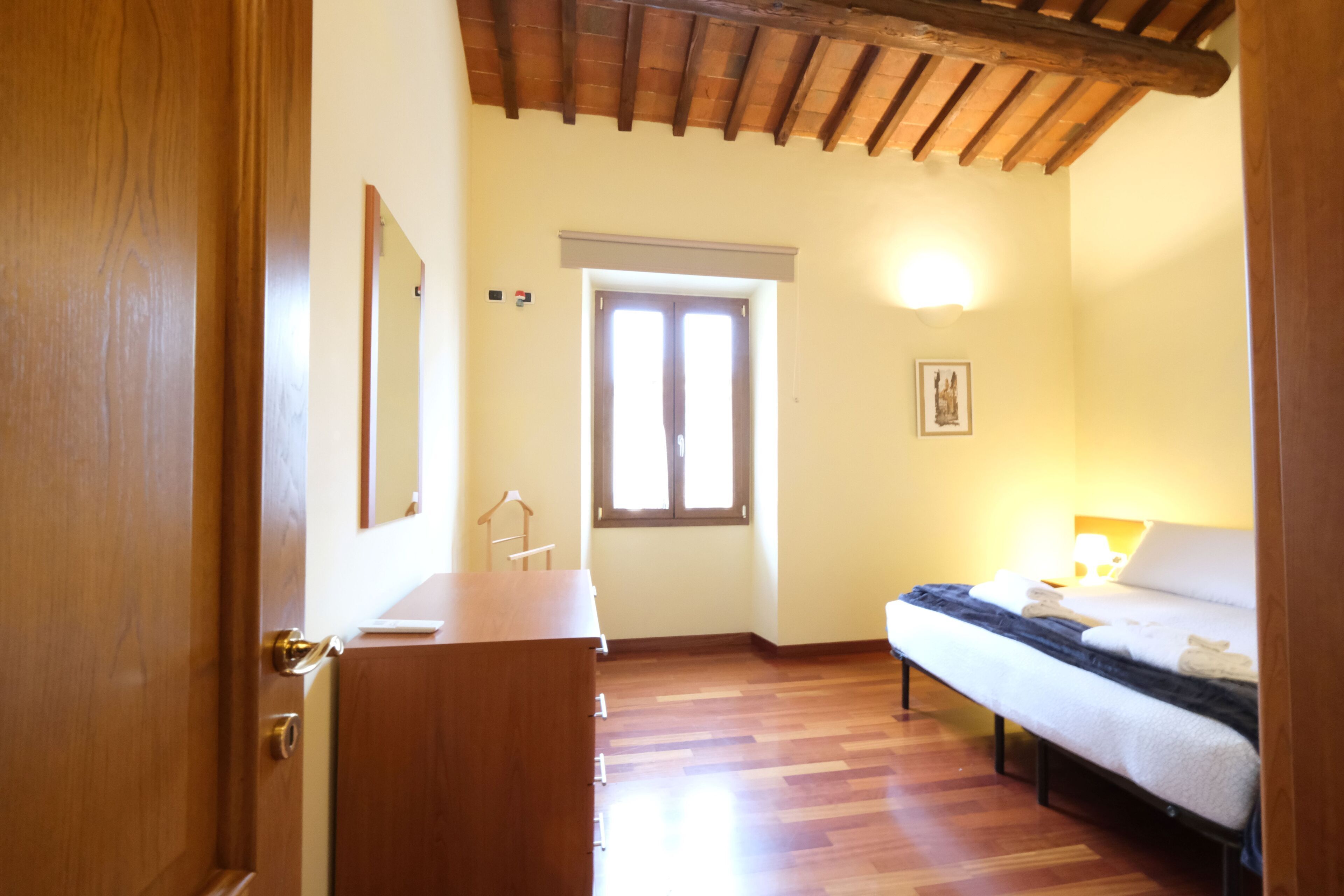 A bedroom with a wooden bed, a dresser, and a window with blinds.