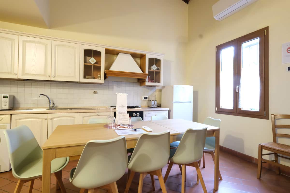 Een keuken met witte kasten, een houten tafel en vier stoelen.