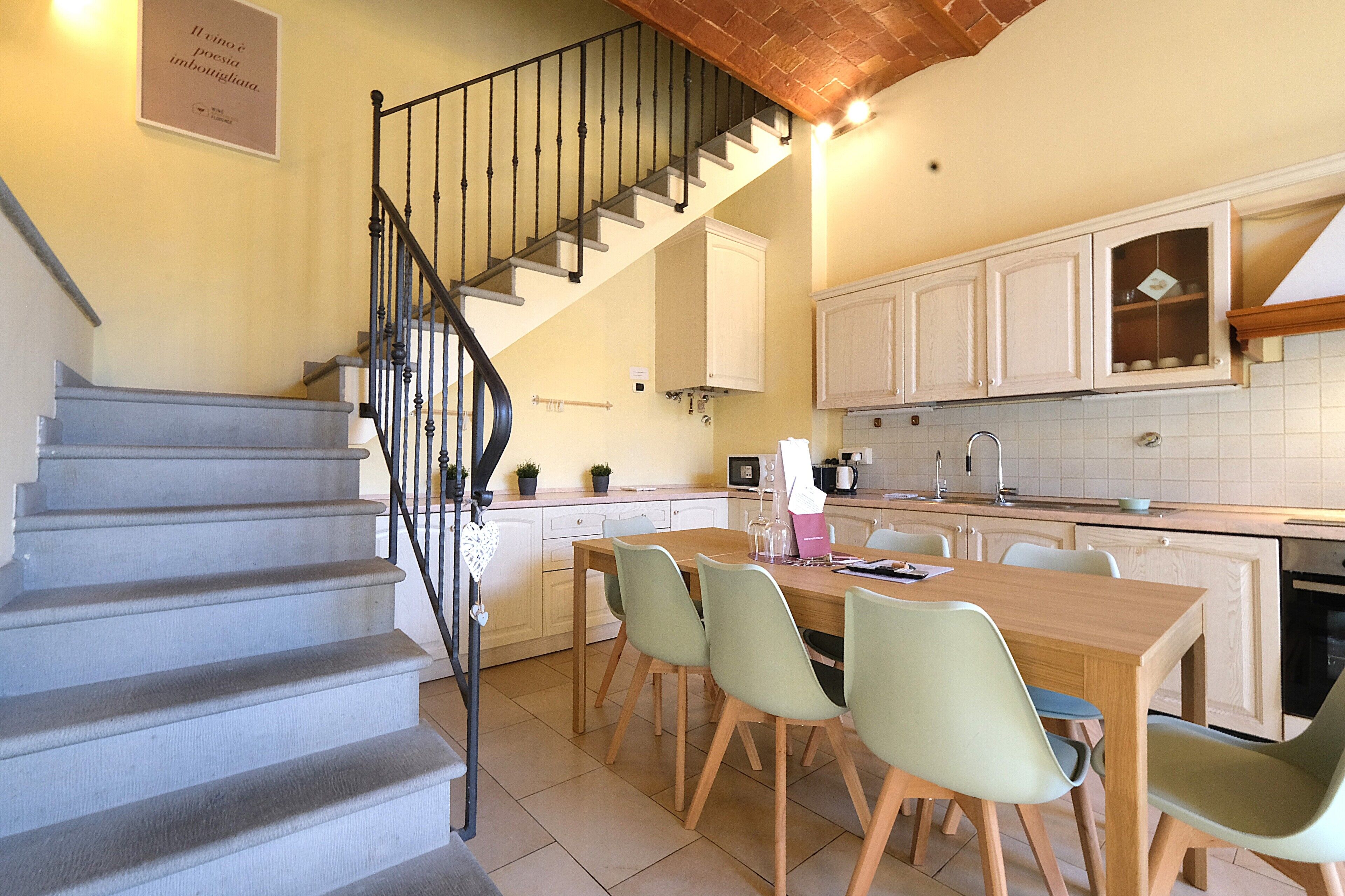 Une cuisine avec une table à manger, des chaises et un escalier.