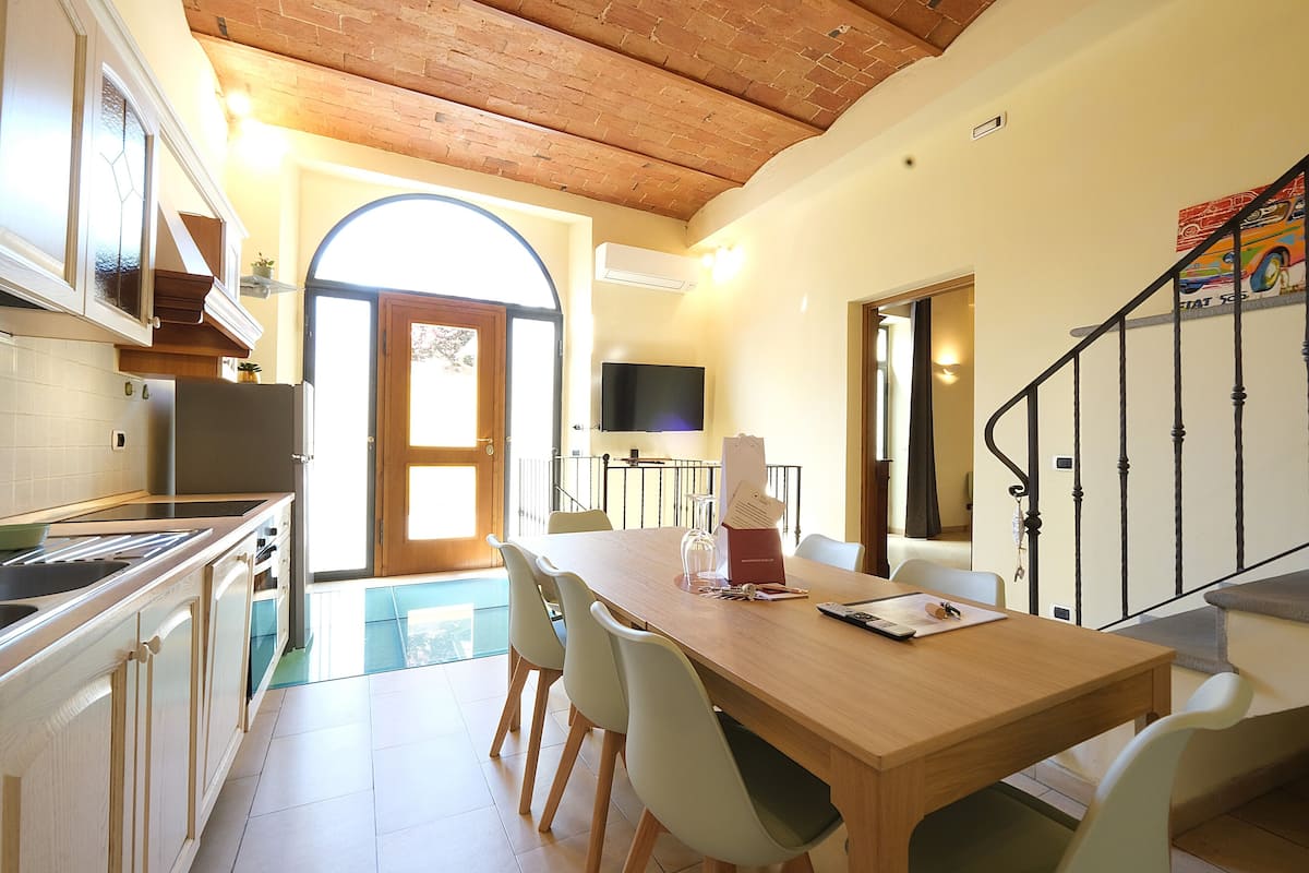 Een moderne keuken met witte kastjes, een houten aanrecht en een eethoek met een houten tafel en stoelen.