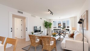 A modern living room with a dining area, a sofa, and a TV. - Avenida Andalucía - iloftmalaga (Málaga)