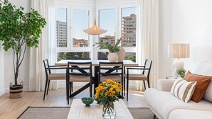 A modern living room with a dining area, large windows, and a view of buildings. - Avenida Andalucía - iloftmalaga (Málaga)