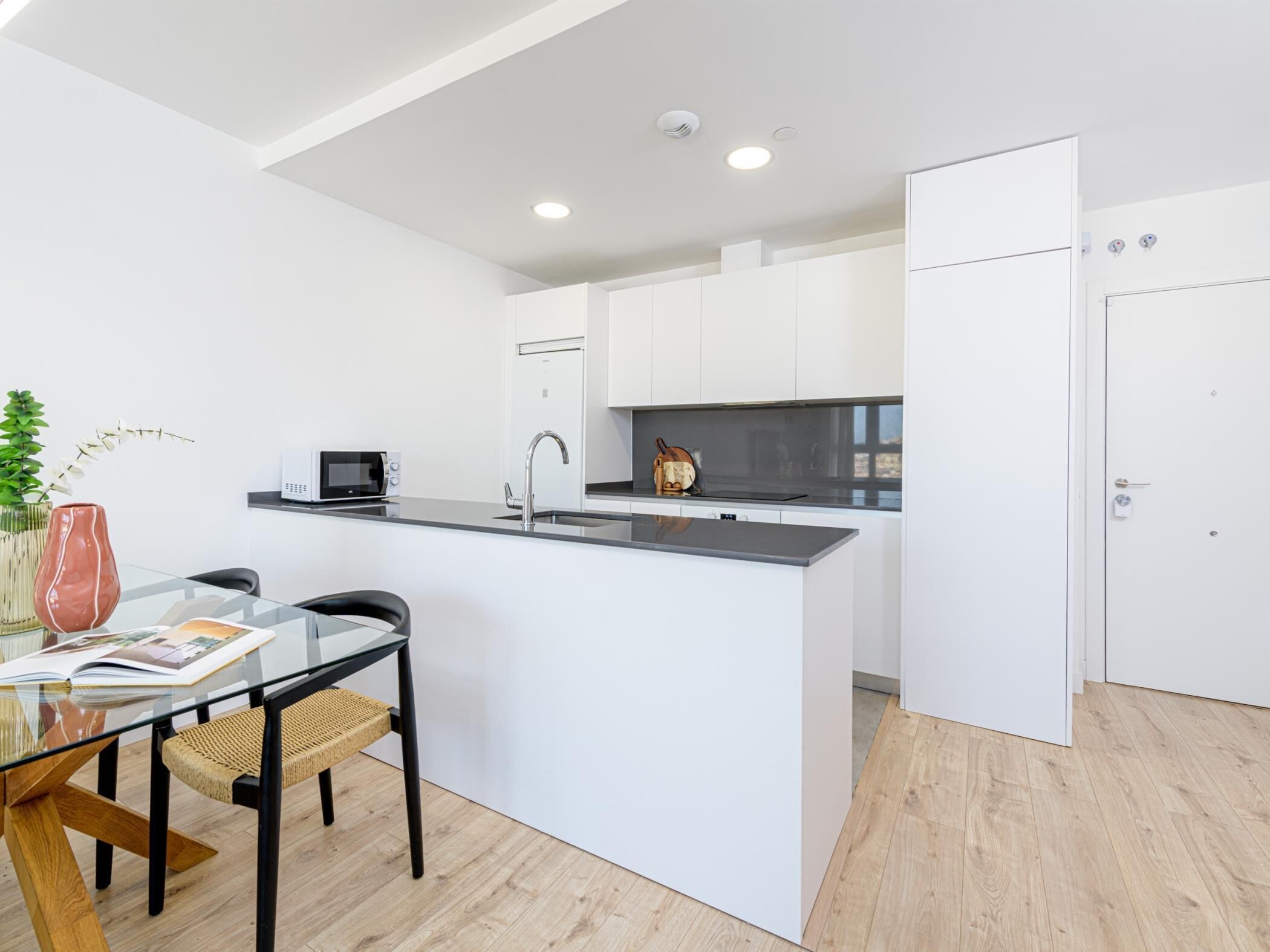 A modern kitchen with white cabinetry, a black countertop, and a built-in microwave.
