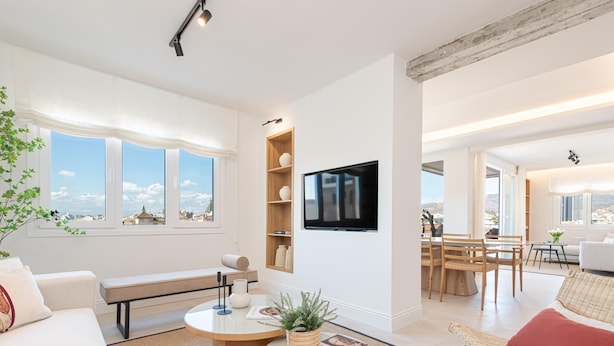 A modern living room with a sofa, a round coffee table, and a TV mounted on the wall.
