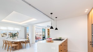 A modern kitchen with a marble island, wooden cabinets, and pendant lighting.