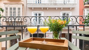 Un plateau en bois sur lequel reposent deux verres de jus d’orange, le tout placé sur un balcon doté d’une balustrade en fer forgé.