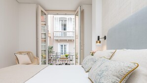 Une chambre d’hôtel avec un lit, une chaise et un balcon équipé d’une table et de chaises.
