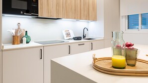 Une cuisine moderne avec des meubles en bois, un micro-ondes noir, un évier et un plateau de petit-déjeuner avec un verre de jus.